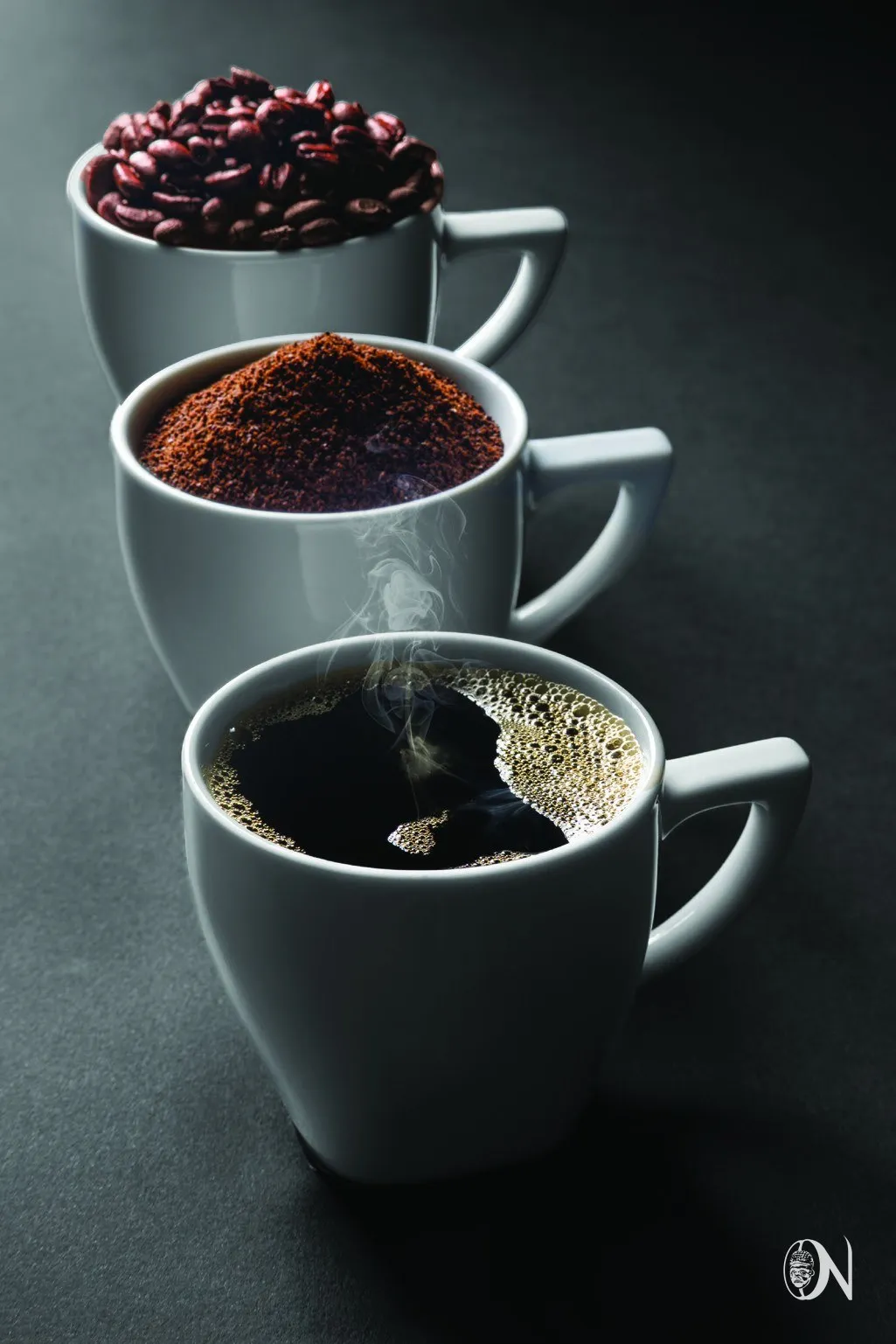 Three cups holding whole beans, ground coffee and a finished brew